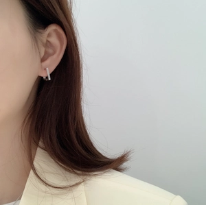 Close-up of minimalist silver rectangular bar stud earrings worn by a female model