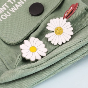 Daisy enamel pins on green canvas bag showing smooth and textured floral centers