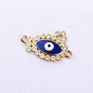 Detailed macro view of gold evil eye jewelry connector with blue enamel and zircons