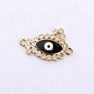 Detailed close-up of a golden evil eye connector with black enamel and zircon stones