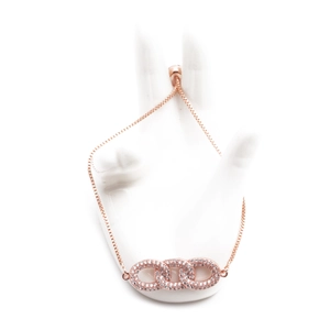 Rose gold adjustable infinity bracelet with triple interlocking zircon loops on a stand