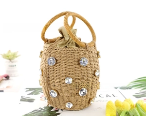 Close-up of straw bucket bag with rhinestone accents and woven round handles