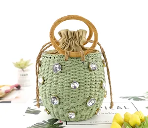 Detail of green straw bucket bag with rhinestone accents and round wooden handles