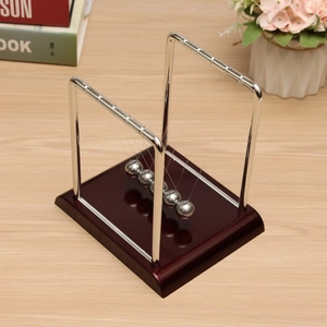 Classic Newton's cradle with metal balls and wooden base on a wooden desk setup