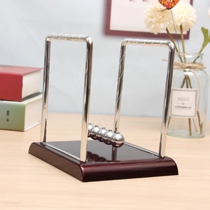 Detail view of five silver metal balls on a dark wooden base Newton's Cradle desk toy