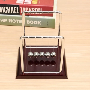 Detail of Newton's cradle with polished metal balls and a brown wood texture base