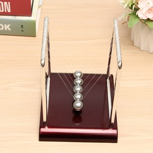 Detailed close-up of Newton's cradle with five silver metal balls on a wooden base