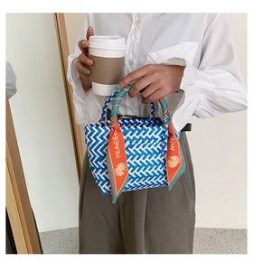 Détail d'un sac à main tissé bleu et blanc avec un foulard en soie décoratif