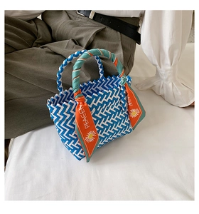 Sac panier tissé bleu et blanc avec un foulard en soie orange sur une anse chic