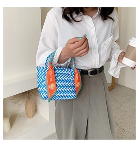 Détail d'un sac en paille avec poignée en foulard de soie orange et motif bleu