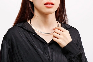 Polished silver-tone choker necklace in minimalist design on a black silk shirt