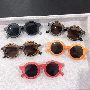 Flat lay of five round kids sunglasses in black, leopard, and matte colored frames