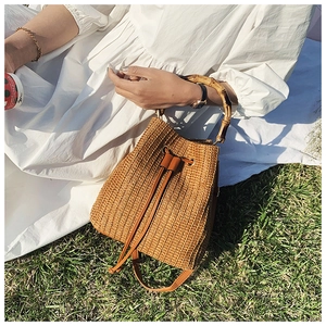 Detailed view of handmade woven straw bucket bag with bamboo handle and leather drawstring