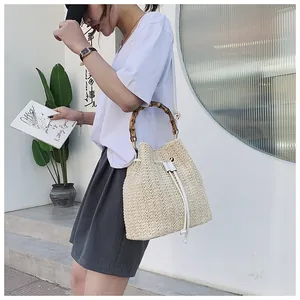 Detail of straw bucket bag with bamboo handle and white leather drawstring closure