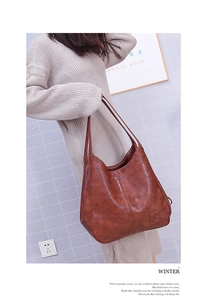 Makro-Detail einer braunen Vintage-Ledertasche mit geometrischen Nähten und Logo-Prägung