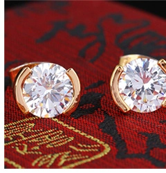 Macro shot of elegant 18K gold-plated earrings with clear zircon stones on textured fabric