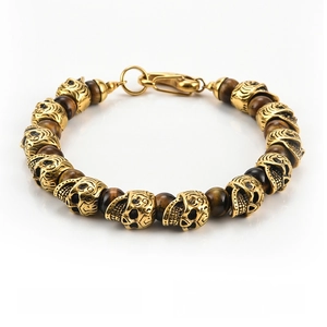 Close-up of punk style multi-layered brown tiger eye beads and gold skull charms bracelet