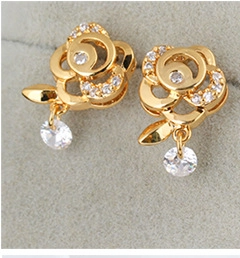 Macro detail of 18K gold plated rose earrings with zircons and crystal pendant