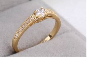 Macro shot of gold ring with round white zircon in a grey velvet jewelry box