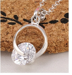 Macro close-up of a round-cut cubic zirconia pendant necklace on a silver-tone thin chain