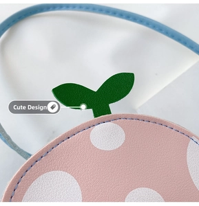 Close-up of pink polka dot girl's shoulder bag with green leaf detail and blue strap