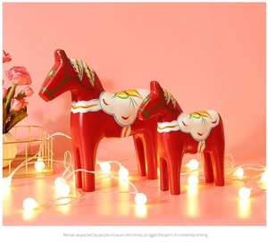 Close-up of two red wooden Dala horses with floral patterns and festive warm lights