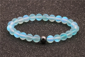 Moonstone and hematite beaded bracelet with frosted blue beads on textured black surface