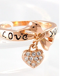 Macro shot of rose gold ring with bow design, zircon heart pendant and Love You engraving