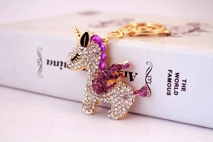 Macro shot of gold unicorn keychain with purple crystals on vintage book background