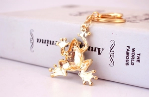 Detailed close-up of a golden crystal frog keychain resting on a vintage book spine