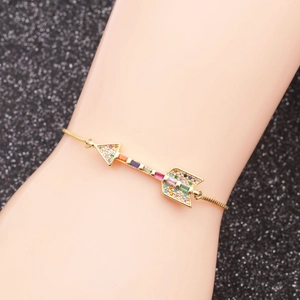 Adjustable gold arrow bracelet with colorful zircon stones worn on a model's wrist