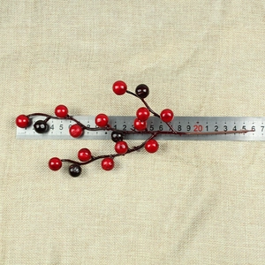Close-up of artificial red berries on a branch with a ruler showing 20cm length