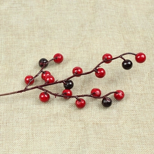 Close-up of red and purple artificial berries on stems over beige linen fabric