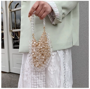 Detail of a handmade clear crystal beaded evening bag with golden metal hardware