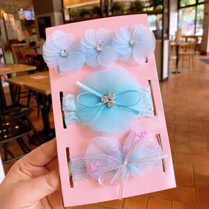 Detailed view of three elastic baby headbands with lace bows and sparkling floral accents
