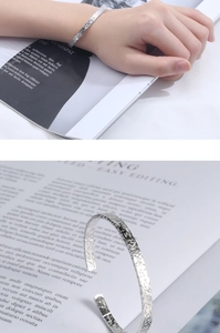 Macro detail of silver cuff bracelet showing unique hammered texture and adjustable design