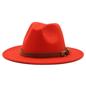 Detail view of red wool fedora hat with brown leather belt buckle and soft texture