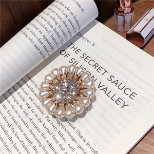 Detail of sunflower phone grip with inlaid crystals and teardrop pearls on vintage book