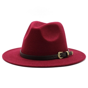 Detail of burgundy wool fedora hat featuring a brown leather strap and gold metal buckle