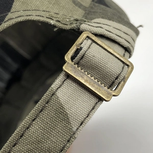 Detail of camouflage canvas cap with adjustable bronze metal buckle and stitching