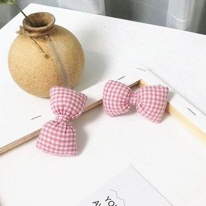 Vue détaillée de deux nœuds en coton à carreaux roses dans un cadre décoratif blanc