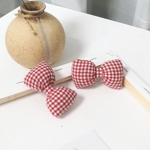 Détail de deux pinces à cheveux noeud en tissu à carreaux rouge et blanc sur fond blanc