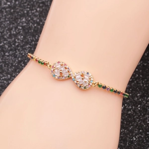 Detail of adjustable gold bracelet with infinity symbols and colorful zircon on a model