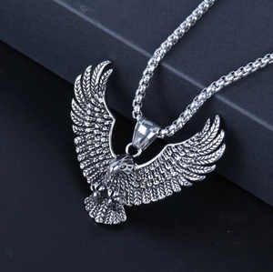 Detailed close-up of a silver eagle pendant with intricate feathers and box chain