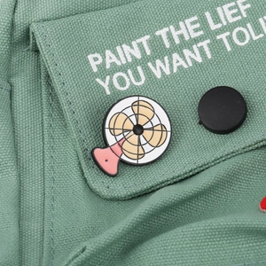Detail of canvas bag with cute cartoon fan enamel pin and decorative button