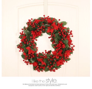 Detail of Christmas wreath with red poinsettias and berries on a white wooden door