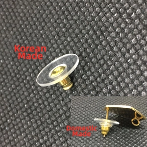 Close-up of brass earring backs and silicone disc stoppers on black textured fabric