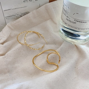 Close-up of 925 silver gold horseshoe ear clips and cuff on textured linen background