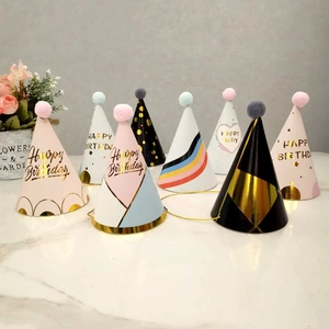 Detail of diverse birthday paper hats with colorful pom-poms and golden elastic strings