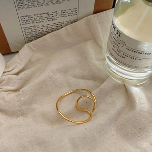Golden double-layer irregular wave ear clips displayed on a rustic linen bag setting
